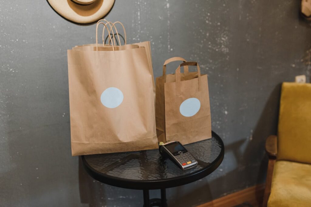 Brown paper bags on a table next to a payment terminal in a cozy room.